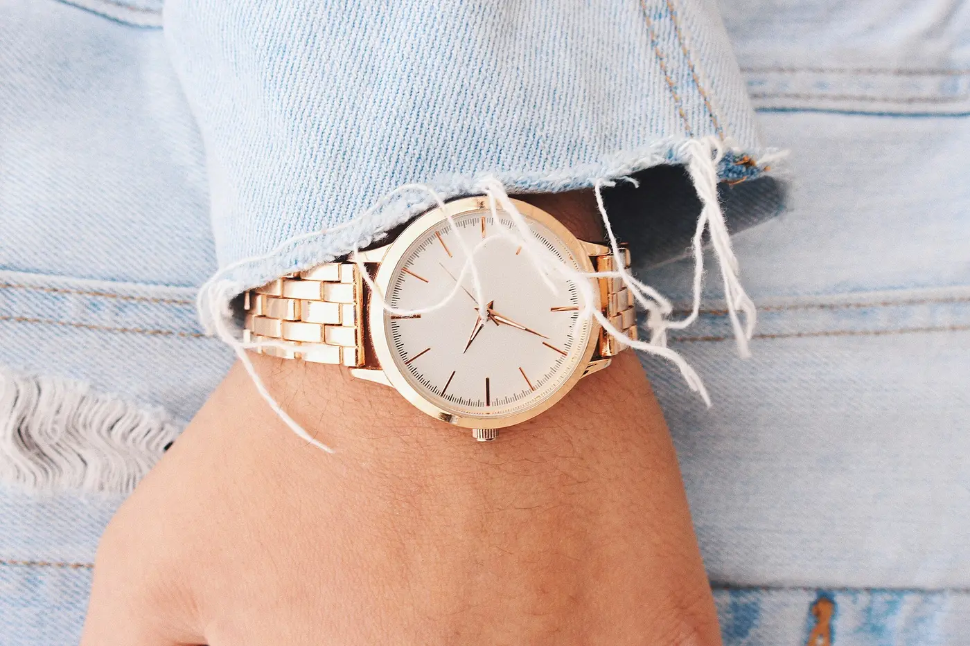 Montre dorée au poignet, manche en jean